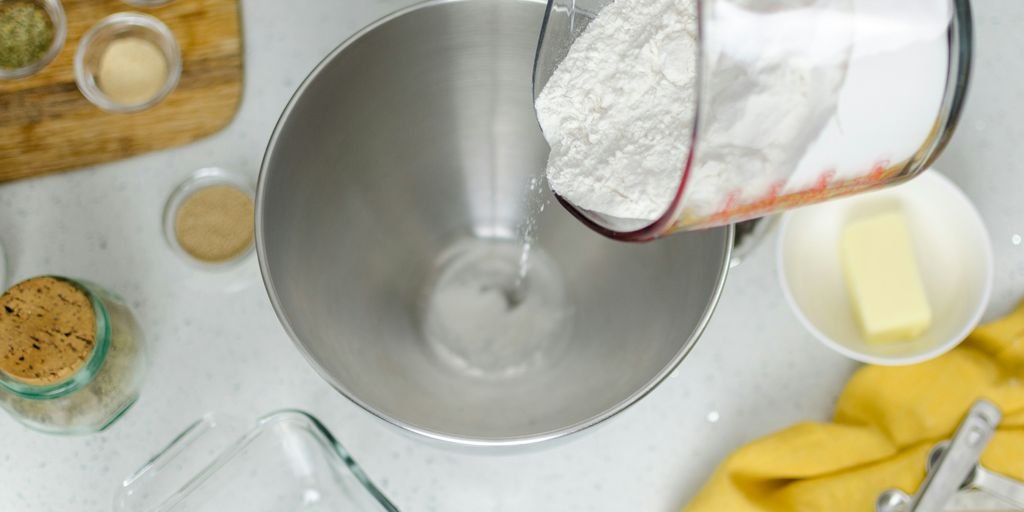 person pouring floor in mixing bowl